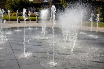 Water droplets spread from the fountain in the air. Splashing water from a fountain in the park....