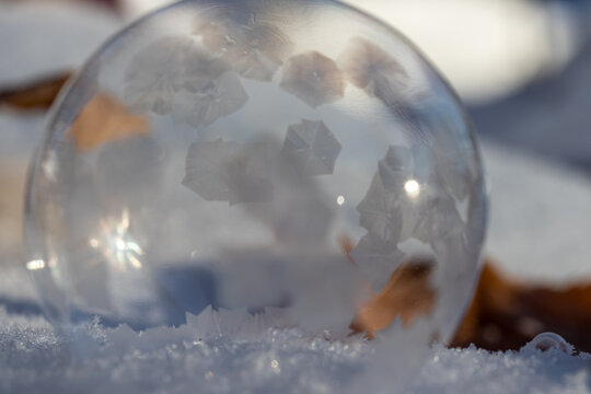 Macro Photo of a Frozen Soap Bubble forming Geometric Ice Crystals as it sits on snow. 