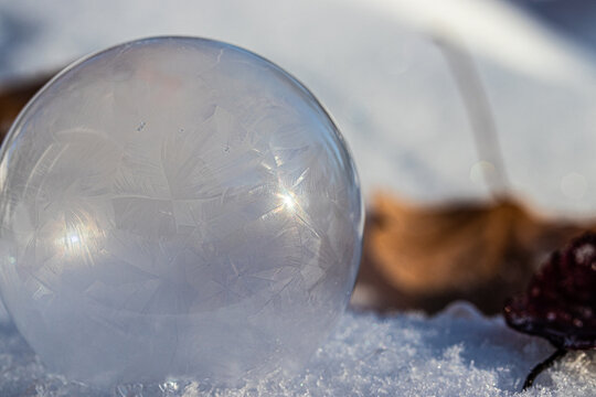 Macro Photo of a Frozen Soap Bubble forming Geometric Ice Crystals as it sits on snow. 