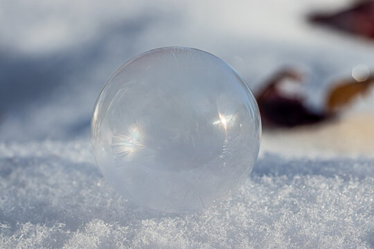 Macro Photo of a Frozen Soap Bubble forming Geometric Ice Crystals as it sits on snow. 