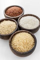 different kinds of asian rice grains in bowls on white background