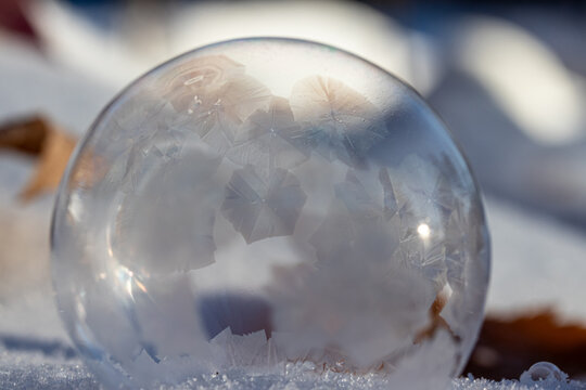 Macro Photo of a Frozen Soap Bubble forming Geometric Ice Crystals as it sits on snow. 
