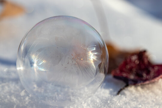Macro Photo of a Frozen Soap Bubble forming Geometric Ice Crystals as it sits on snow. 