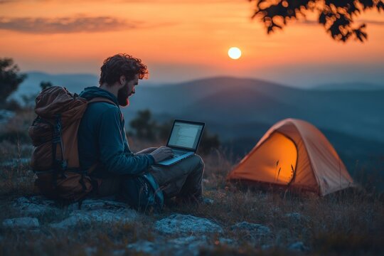 Digital nomad working remotely on laptop in mountains at sunset near tent - Powered by Adobe