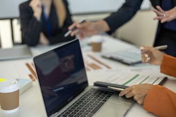 A woman in an orange shirt is looking at a piece of paper with graphs on it. She is holding a cup of coffee in front of her. The scene suggests that she is working on a project or analyzing data

