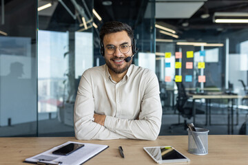 Webcam view, man with headset looking into camera, smiling contentedly. Support service worker at...