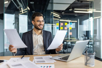 Successful financier doing paperwork inside office. Businessman in business suit holding papers,...