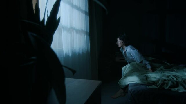 Young woman in pajama standing up from her bed, sleepwalking at night in her modern eco-friendly bedroom