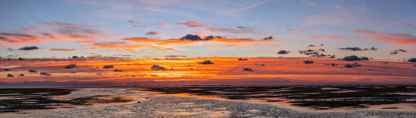 Panoramaaufnahme eines stimmungsvollen Sonnenuntergangs mit überschwemmtem Vorland auf der Nordfriesischen Insel Föhr