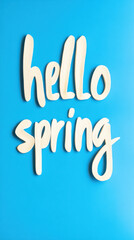 Wooden letters spelling hello spring lie on a vibrant blue background, creating a cheerful announcement of the new season's arrival and evoking feelings of renewal and warmth