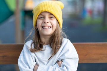 Portrait of cheerful pretty girl in yellow cap with freckles on face looking at camera while...