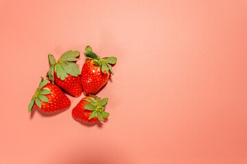 Four strawberries on a pink background. The strawberries are in the center of the image