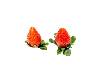 Two strawberries are on a white background. They are both red and have green leaves on top. The strawberries are placed close to each other