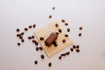 Chocolate, coffee beans, and a waffle on a white background.