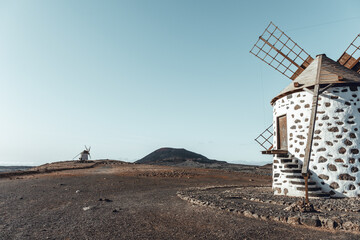 View of the old, typical windmills of Villaverde, Fuerteventura, Canary Islands, with their wooden blades. almost sunset, oblique light, golden hour. Past, vintage feeling.