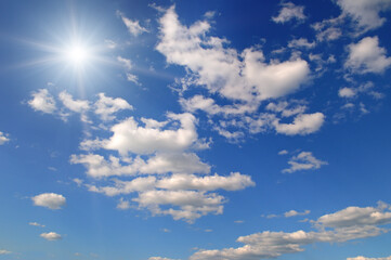 Blue sky with white clouds and bright sun.