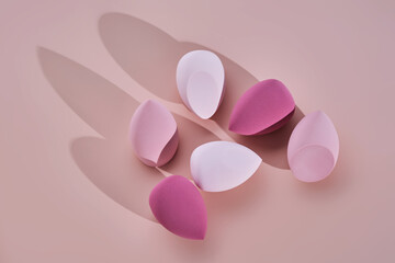 A set of makeup sponges on a pink background.