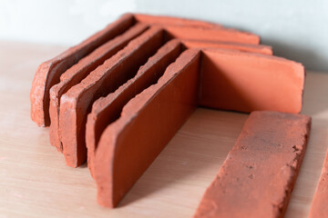 A close-up of red clay bricks neatly stacked and aligned on a wooden surface, showcasing texture and color contrast.