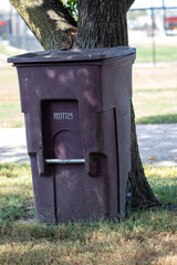 Park trash can by large tree close up. High quality photo
