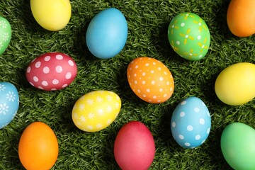 Beautiful decorated Easter eggs on green grass, flat lay
