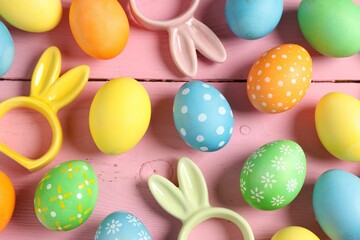 Beautiful decorated Easter eggs and bunny figures on pink wooden table, flat lay