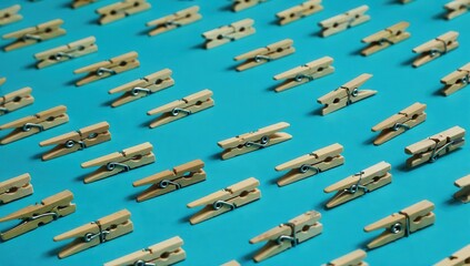 Naklejka premium A repeating pattern of wooden clothespins, evenly spaced on a bright cyan background.