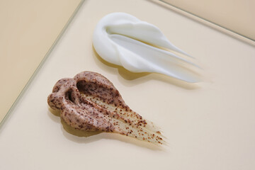 A smear of white cream and coffee cream scrub on a beige background.