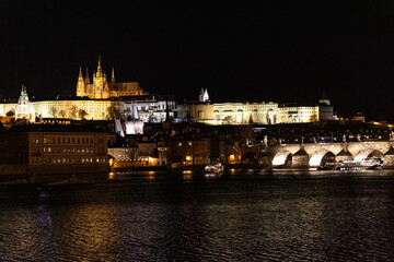 Sunset colors in Prague Historical Gothic Medieval castle, St. Vitus Cathedral, Charles Bridge and river Vltava boat cruise, astronomical clock, Unesco city tourism, night view and water reflection