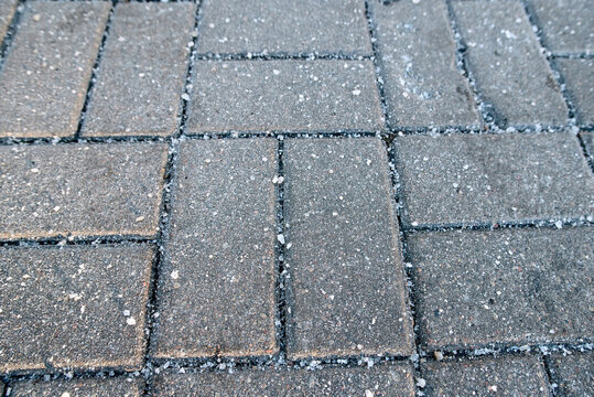 Salt crystals on paving stone slabs in winter, surface treatment methods for preventing ice buildup and slippery hazards. Paving slabs with visible salt crystals in winter season - Powered by Adobe