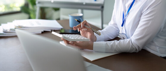 Fototapeta premium Accountant analyzing financial documents with a calculator, highlighting attention to detail in financial reporting.