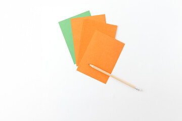 four rectangular pieces of paper, three orange and one green, arranged in a fanned-out manner on a...
