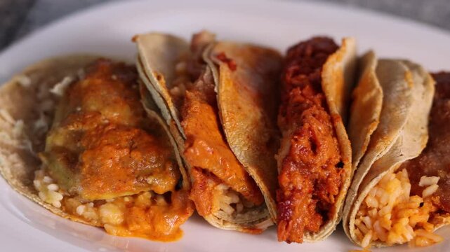Preparation of three different delicious tacos with various ingredients on a white plate