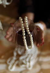 A glass of red wine with a string of pearls. aesthetic composition