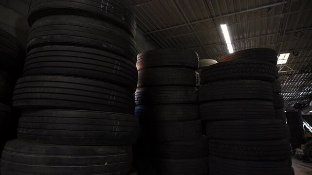 The warehouse or storage area filled with large stacks of tires. The tires are piled high, creating a sense of depth and bulk.
