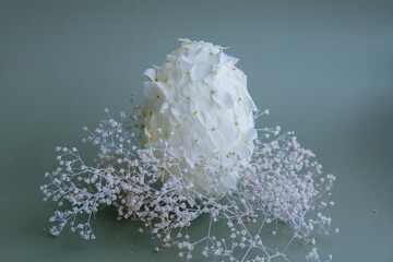 Easter egg made of white lilac spring flowers in pastel green background. Sustainable holiday...