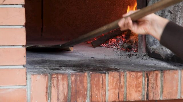 Woman making bread, close-up shot, wood-fired oven baking process.