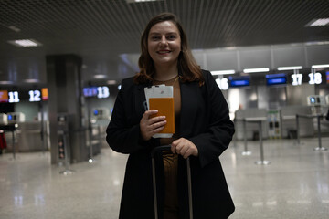 Portrait of Caucasian traveler woman hold ticket ready enjoy voyage tour passenger walk in airport terminal to boarding gate. Attractive beautiful female tourist excited to go travel abroad by