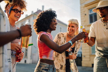 Group of diverse friends toasting with drinks at a summer festival