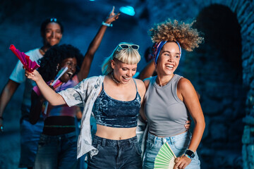 Friends embracing and dancing, enjoying music festival at night