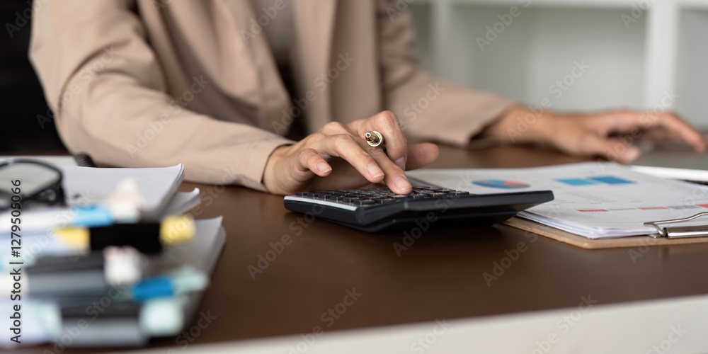 Aufkleber accountant using a calculator to manage financial data and reviewing documents at a desk.