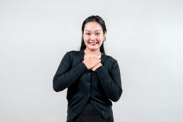 A young woman in a black cardigan places her hands on her heart, smiling warmly. This gesture symbolizes gratitude and sincerity, perfect for themes of kindness and compassion.