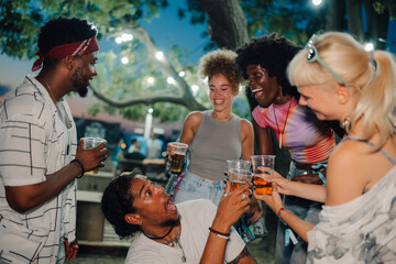 Friends toasting with beer at outdoor summer music festival