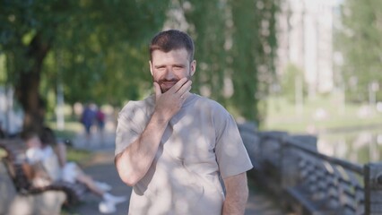 A man dressed in casual attire is lost in deep thought while being surrounded by nature in a...