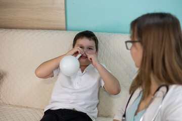 A doctor consults a child at home. A boy learns to use a nasal blower under the guidance of a...