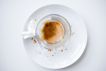 Empty cappuccino cup on white plate with crumbs and tissue