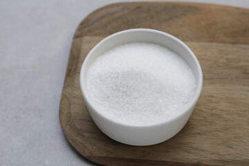 Monosodium glutamate in bowl on wooden background.