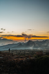 A person standing in front of a foggy and misty mountain peak at sunset in Kilimanjaro Tanzania Africa