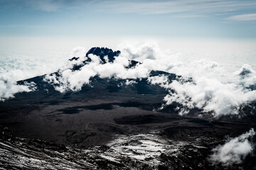 A mountain peak covered in clouds as seen from Uhuru Peak of Mount Kilimanjaro in Tanzania Africa