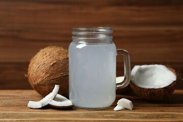 Mason jar with coconut water with nuts on wooden table