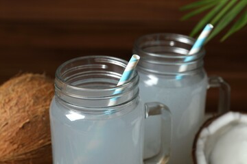 Mason jars with coconut water with nuts on wooden table